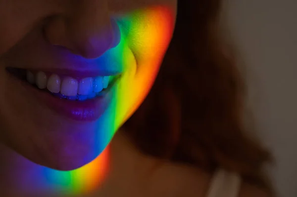 Retrato de cerca de una mujer sonriente con rayo de luz del arco iris en su cara. —  Fotos de Stock