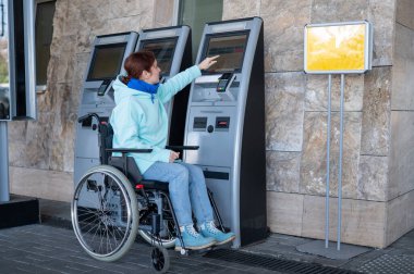 Tekerlekli sandalyedeki beyaz kadın self-servis kasasından tren bileti alıyor.. 