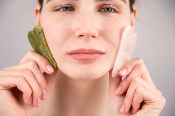 Retrato de cerca de una mujer sosteniendo dos rascadores cerca de su cara. — Foto de Stock