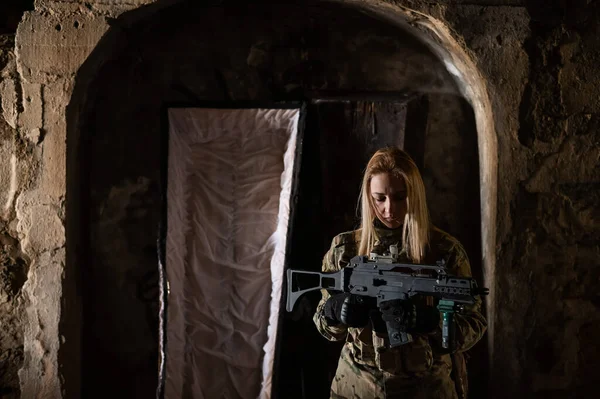 Blanke vrouw in legeruniform die een machinegeweer vasthoudt en bij een open kist staat. — Stockfoto