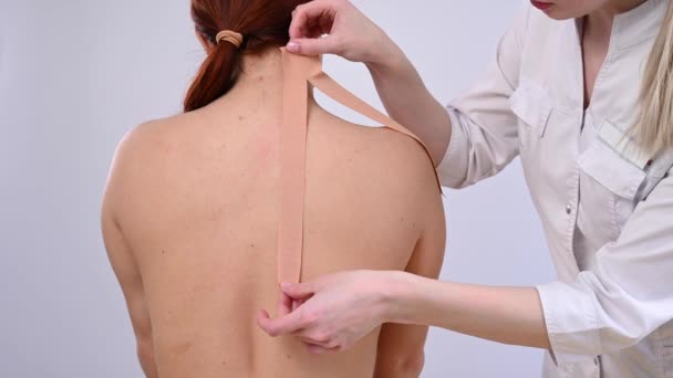 Médico femenino pega cintas kinesio en el hombro de los pacientes. — Vídeo de stock