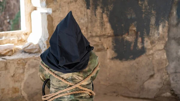 Caucasian woman is taken hostage tied with a rope and with a black bag on her head. — Stock Photo, Image
