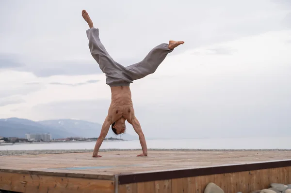 Shirtless blanke man doet acrobatische wiel op het strand. — Stockfoto