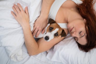 Kafkasyalı kadın yatağında uyuyor sevgili köpeğine sarılıyor..