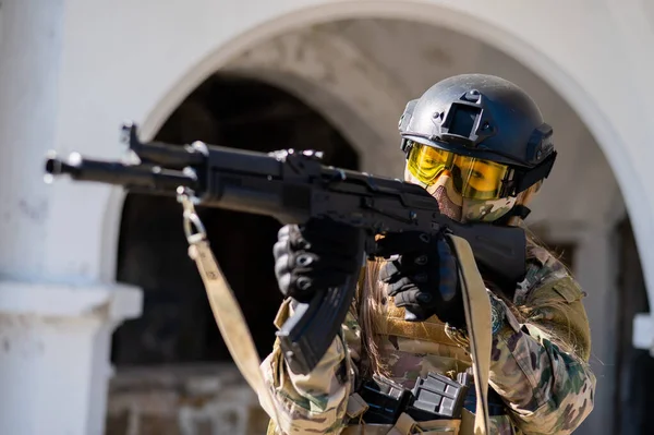 Blanke vrouw in een beschermend pak met machinegeweer. Een vrouwelijke soldaat in camouflage uniform heeft een wapen.. — Stockfoto