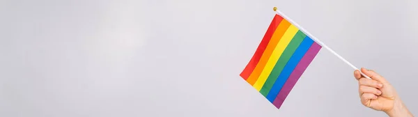 Una mujer sostiene una bandera del arco iris sobre un fondo blanco. — Foto de Stock