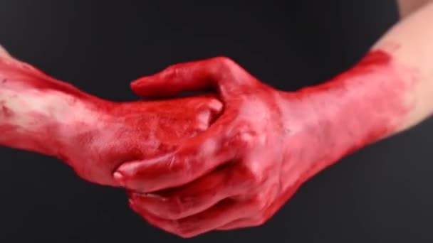 Una mujer se frota las manos manchadas de sangre sobre un fondo negro. — Vídeo de stock
