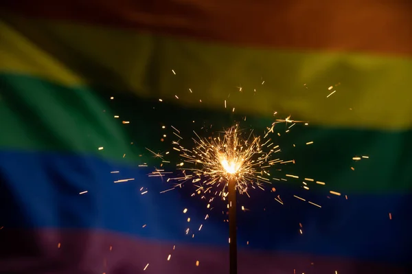 Sparklers met golvende lgbt regenboog vlag achtergrond. — Stockfoto