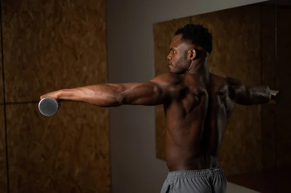 Atraente homem americano africano fazendo exercícios de braço com halteres. — Fotografia de Stock