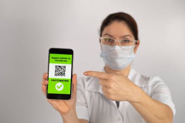 Doktor aşı öneriyor ve QR kodlu bir akıllı telefon tutuyor..