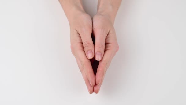 Een vrouw opent haar handen en toont een rood lint op een witte achtergrond. Symbool van de strijd tegen aids. — Stockvideo