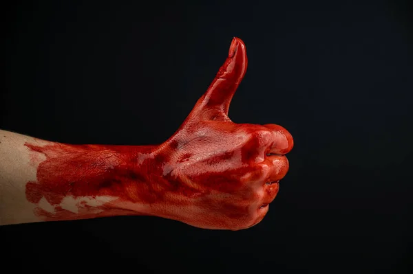 Una mano de mujer manchada de sangre muestra un pulgar hacia arriba sobre un fondo negro. — Foto de Stock