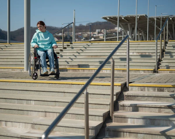 Μια λευκή γυναίκα σε αναπηρικό καροτσάκι δεν μπορεί να κατέβει σκάλες χωρίς ράμπα. Δύσκολο στην πρόσβαση περιβάλλον. — Φωτογραφία Αρχείου