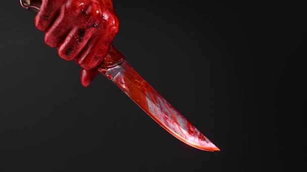 Man som håller kniv med blodig hand på svart bakgrund. — Stockvideo