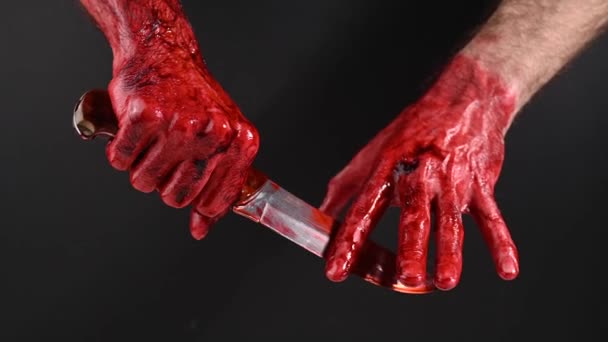 05.04.2022 Ryssland, Novosibirsk: En man torkar en kniv ur blodet med handen på svart bakgrund. — Stockvideo