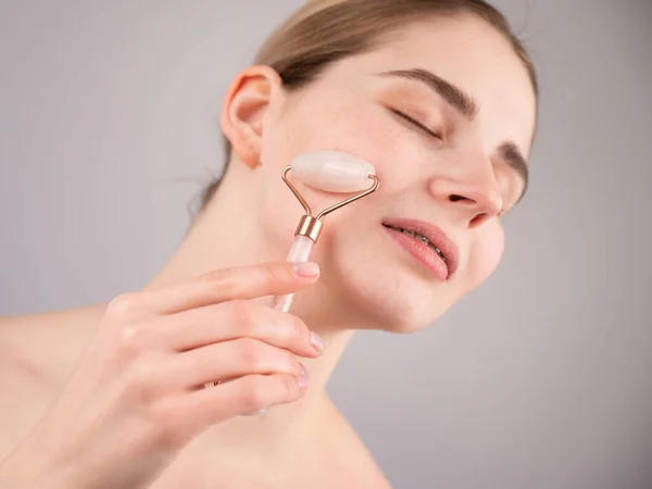 Detailní záběr portrét ženy, která používá na tváři masážní zařízení na křemen pro alternativní anti-aging. — Stock fotografie
