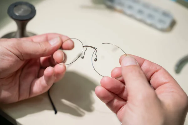 A man repairs a broken eyeglass frame. Close-up of the ophthalmologists hands