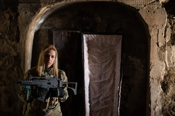 Biała kobieta w mundurze wojskowym trzymająca karabin maszynowy i stojąca przy otwartej trumnie. — Zdjęcie stockowe
