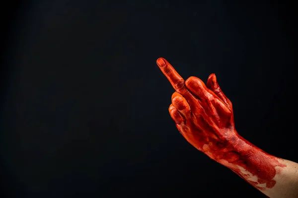 Mano femminile macchiata di sangue mostra il dito medio su uno sfondo nero. — Foto Stock