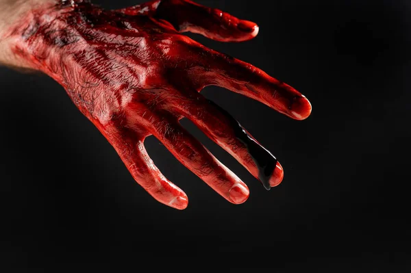 Närbild av en manlig hand färgad med blod på en svart bakgrund. — Stockfoto