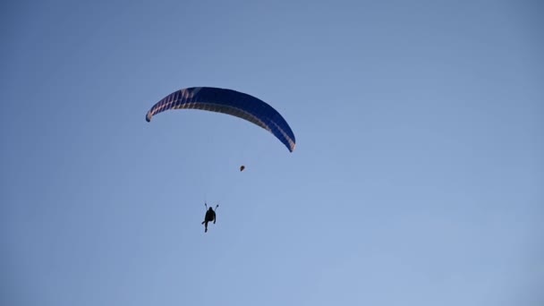 Silhouette eines Mannes auf einem Gleitschirm im blauen Himmel. — Stockvideo