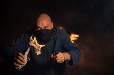 Maskeli bir adam yanan bir şişe tutuyor. Molotof kokteyli.