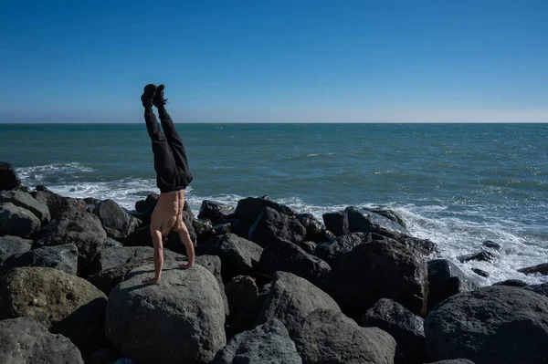 海のそばの岩の上に立つ白人の男. — ストック写真