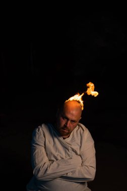 Kel bir adam, deli gömleği ve koyu bir arka planda yanan bir kafası var..