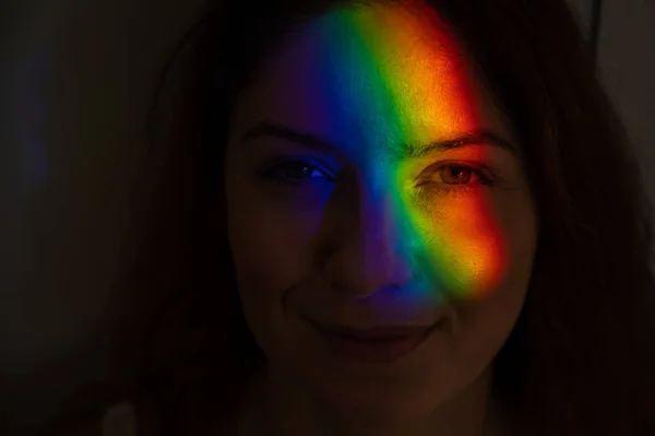 Närbild porträtt av kaukasiska kvinna med stråle av regnbåge ljus i ansiktet. — Stockfoto