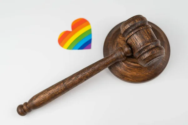 Martillo judicial y corazón con bandera de arco iris sobre fondo blanco. Proteger los derechos de los homosexuales en los tribunales. —  Fotos de Stock