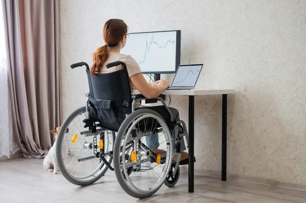 Mulher branca em uma cadeira de rodas digitando com um laptop de casa. Trabalho remoto para pessoas com deficiência. — Fotografia de Stock