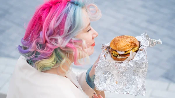 곱슬머리의 백인 여성 이 햄버거를 먹고 있어요. 나쁜 식사 습관 과 패스트푸드에 대한 사랑 — 스톡 사진