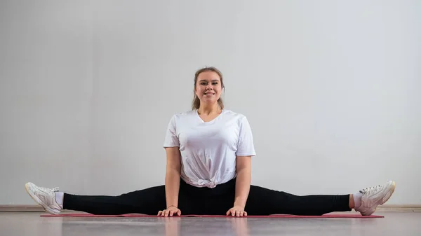 Paffuto giovani donna fare stretching su bianco sfondo. — Foto Stock
