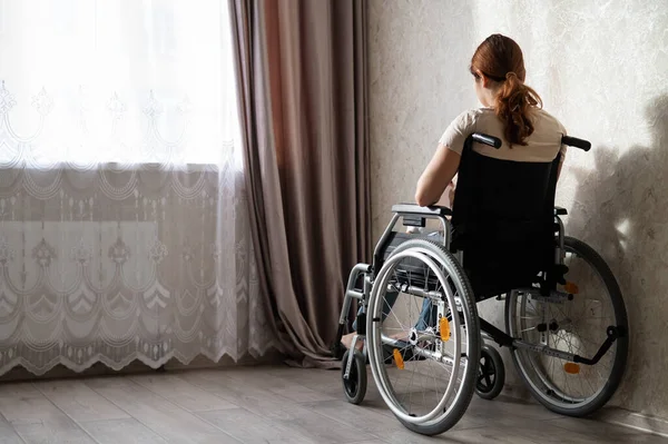 Blanke vrouw in een rolstoel bij het raam. — Stockfoto