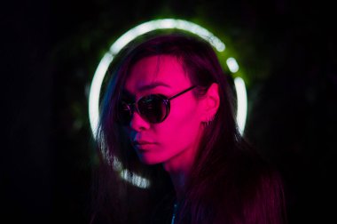 Neon ışıkta güneş gözlüğü takan Asyalı adamın portresi. 