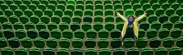 Vit kvinna hejar på ett idrottslag på stadion. Flickan tittar på matchen på arenan ensam. — Stockfoto