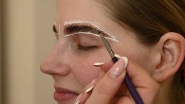 Üstat boyamadan önce beyaz boyayla kaşların şeklini çizer.. 