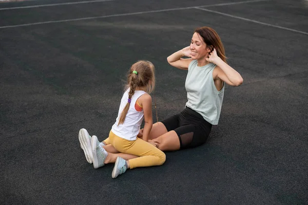 Мать и дочь занимаются спортом на свежем воздухе. Кавказка и девочка занимаются фитнесом на стадионе. — стоковое фото