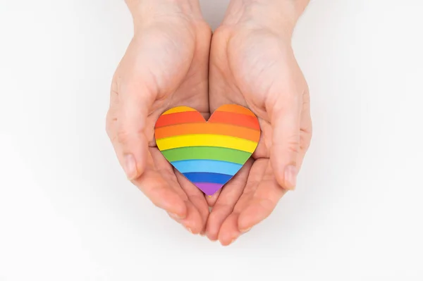 Manos femeninas con corazón de papel arco iris aisladas sobre fondo blanco. —  Fotos de Stock