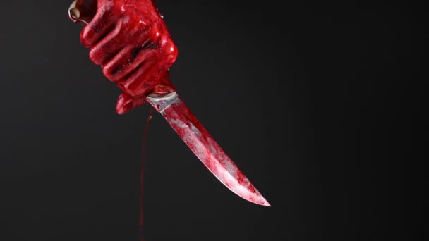 Man som håller kniv med blodig hand på svart bakgrund. — Stockvideo