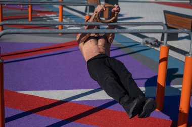 Spor sahasındaki paralel çubuklarda üstsüz adam yatay denge yapıyor.. 
