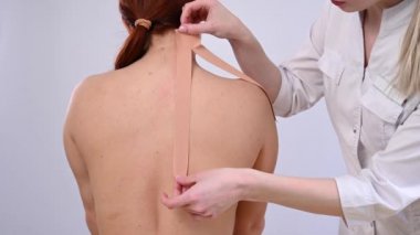 Kadın doktor hastaların omzuna kinesio bantları yapıştırıyor.. 