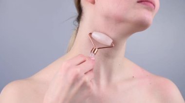 Boynundaki kırışıklıklara karşı alternatif bir dövüş için kuvars silindirli masaj aleti kullanan bir kadının yakın plan portresi. Venüs 'ün halkalarının yumuşaklığı. 