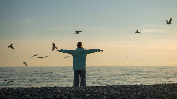 Femme caucasienne écarta ses bras comme des ailes sur le bord de la mer au coucher du soleil. — Photo