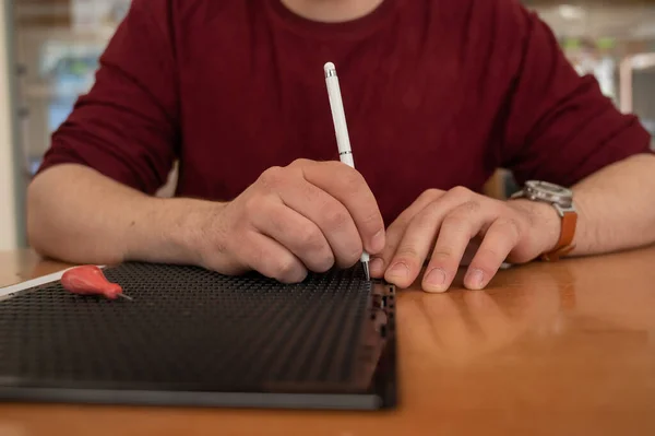 Un hombre usa un lápiz especial para escribir una carta en braille. — Foto de Stock