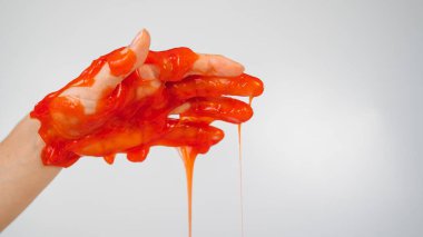 Beyaz arka planda bir kadının elinden akan kırmızı balçık.. 