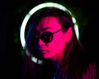 Neon ışıkta güneş gözlüğü takan Asyalı adamın portresi. 
