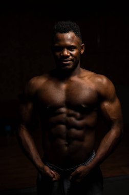 Karanlık bir stüdyoda çıplak gövdesi olan Afro-Amerikan bir adamın portresi. Kaslı adam..