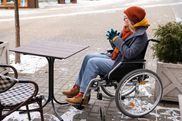 Blanke vrouw in rolstoel zittend aan terrastafel. — Stockfoto