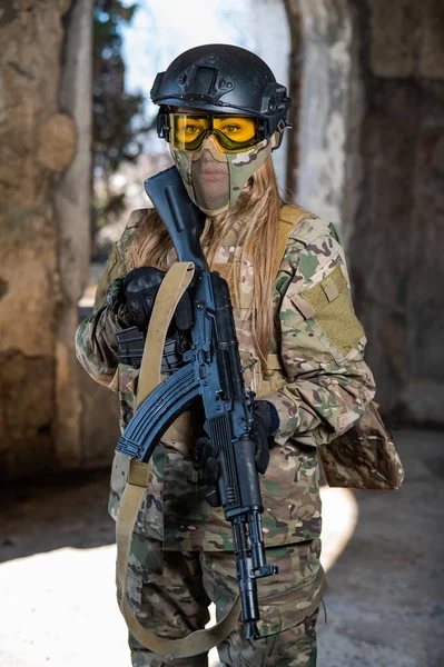 Portrét ženy v helmě a brýlích s kulometem v rukou. Ženský voják v maskovací uniformě drží zbraň.. — Stock fotografie